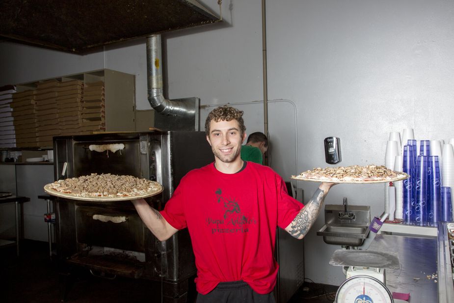 An employee at Papa Angelo's Pizzaria in Bethany holds two Empire-sized pies aloft before putting them in the oven. Photo by Lori Duckworth.