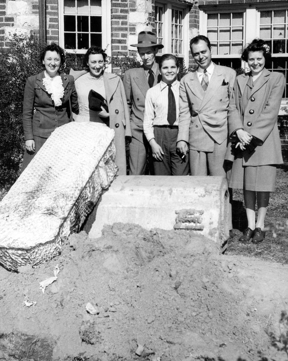 From left to right: Marion Sample, her sister Virginia Evans, Deputy W.S. Duggins, house resident Bobby Gene Fowler, Paul Horner, and his sister Willetta Horner pose next to unearthed dog coffins at the Hex House in Tulsa after the two women were freed. Photo courtesy Tulsa World